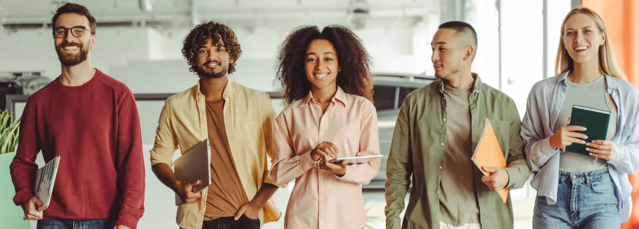 Five employees walking in an office looking happy 