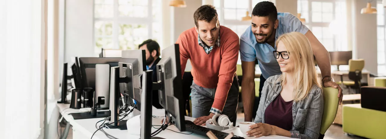 Three employees gathered around a computer 