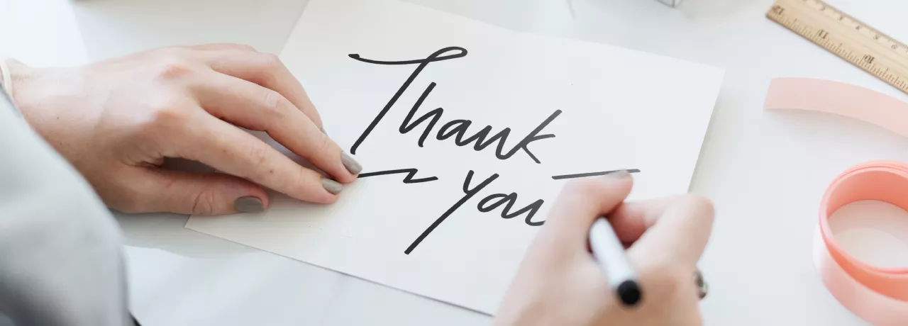 Person writing a thank you note 