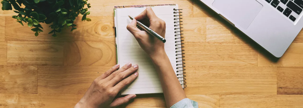 A person writing a note in a journal 