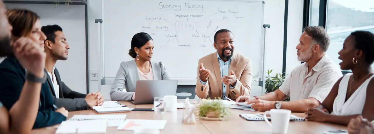 Coworkers sitting around a table with the focus on a one employee in the middle 