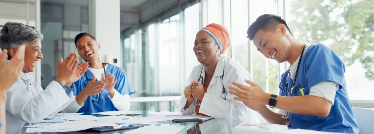 A small group of healthcare workers laughing and smiling at a table 
