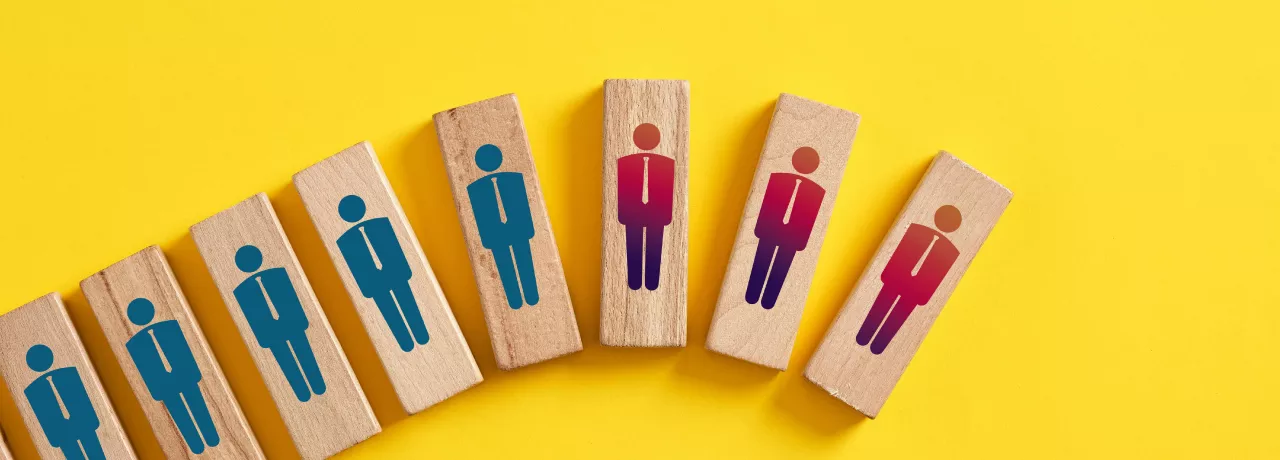 Shows wood blocks with peoples figures on them. The blocks are in a line, inclining. The last three are red and down turned. 