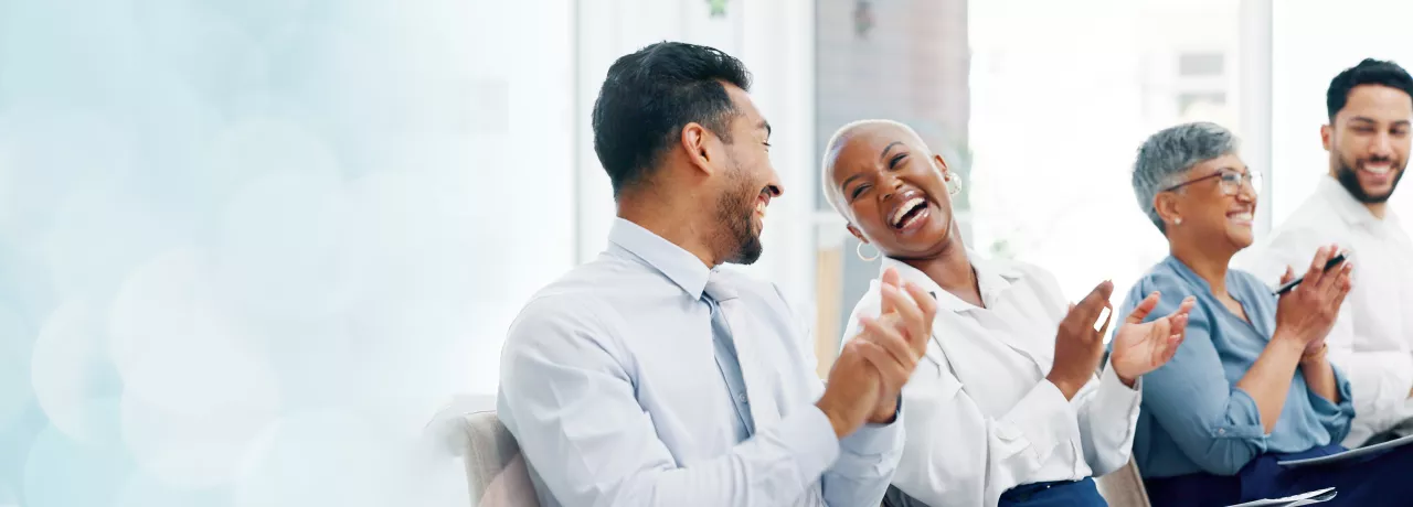 Image shows two employees laughing together along with two others in the background. 