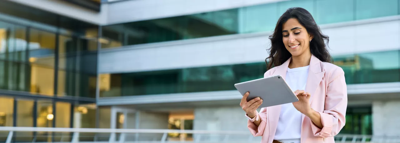 A woman in business clothes smiling down at her tablet 