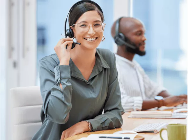 An employee smiling at the camera with a headset on