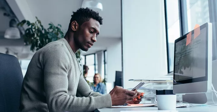 guy at desk using cell phone