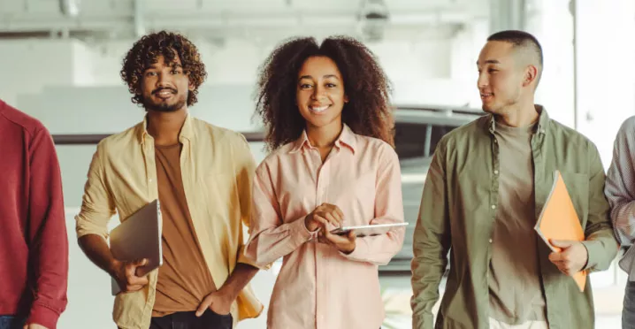 Five employees walking in an office looking happy