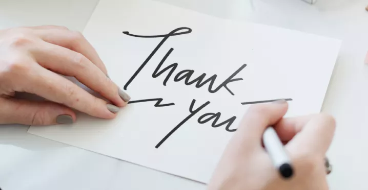 Person writing a thank you note