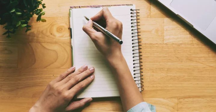 A person writing a note in a journal