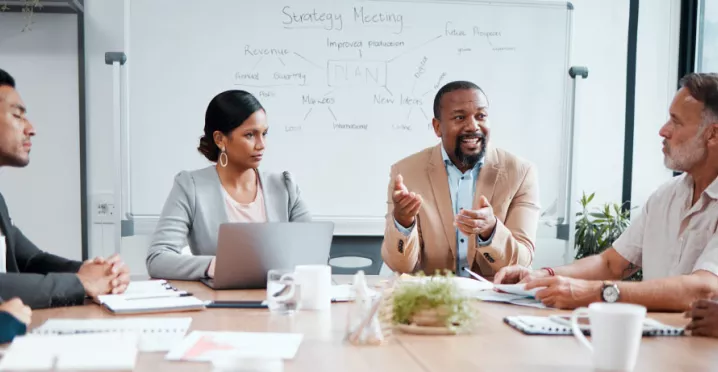 Coworkers sitting around a table with the focus on a one employee in the middle
