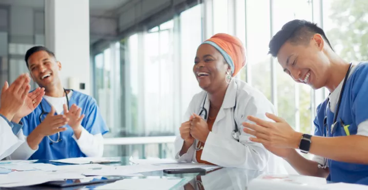 A small group of healthcare workers laughing and smiling at a table