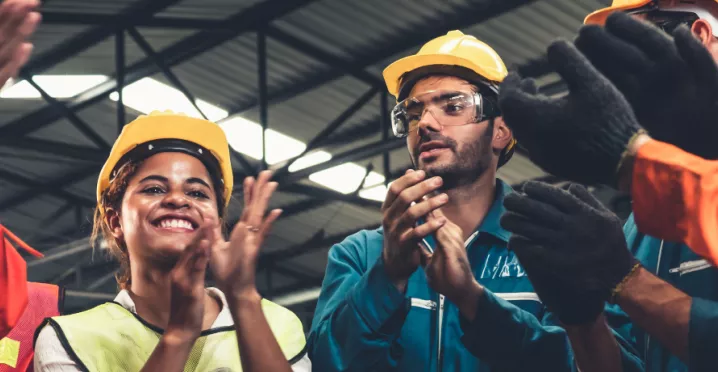 A photograph of construction workers clapping in a circle