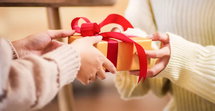 A person handing a gift to another person