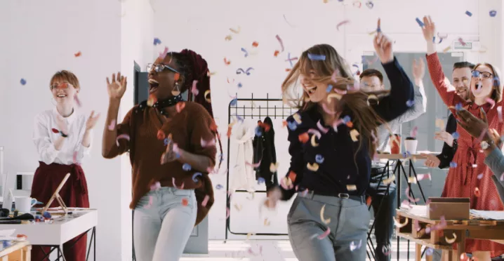 A team celebrating at work with confetti falling down in the background