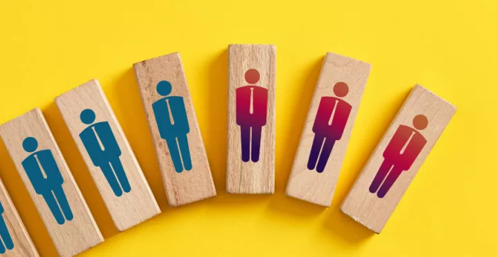 Shows wood blocks with peoples figures on them. The blocks are in a line, inclining. The last three are red and down turned.