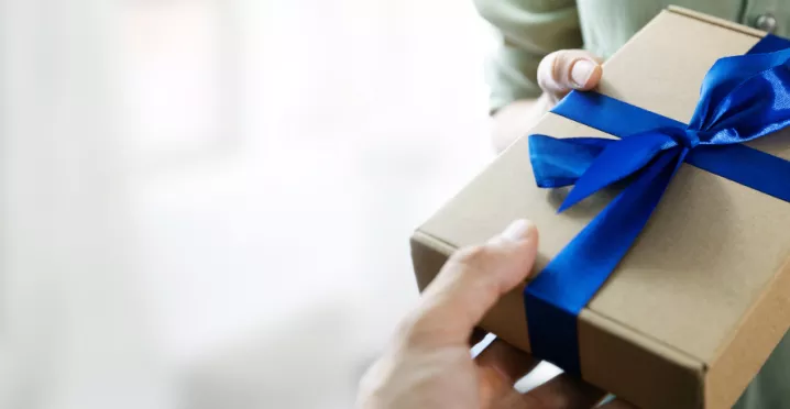 Image shows a person handing a gift to another person