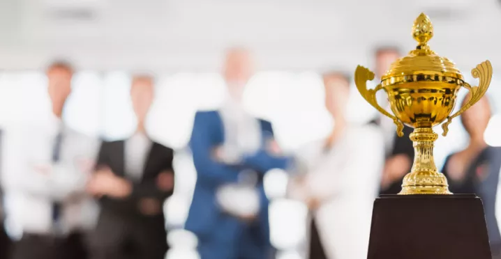 Image shows a trophy sitting in front of a group of employees