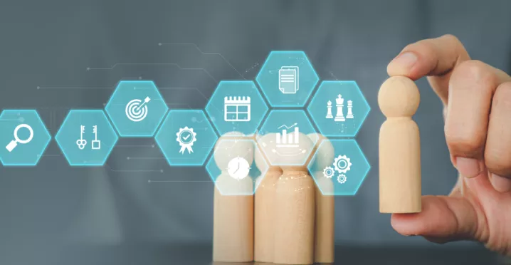 Image shows a person moving a wooden figure with various business symbols in front