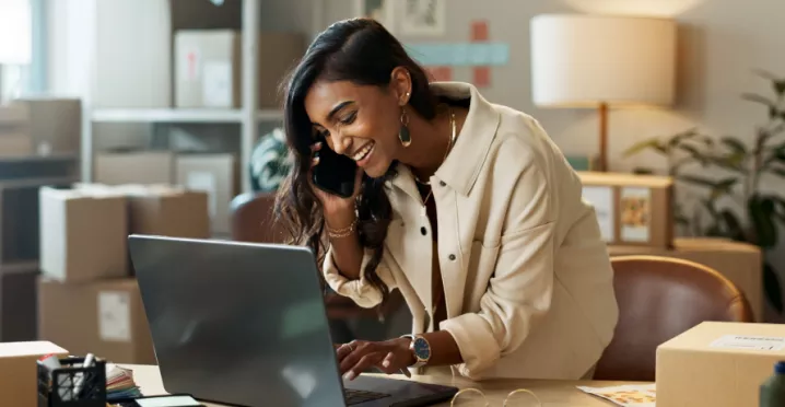 Image shows a woman looking down at her computer and smiling
