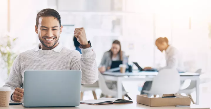 Image shows an employee celebrating by their computer.