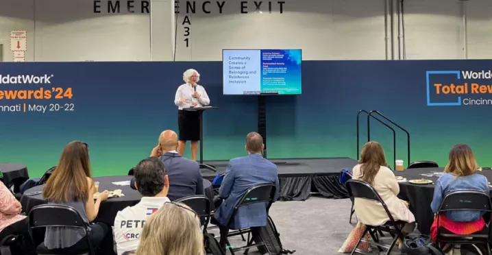 Image shows Theresa Harkins-Schulz, Inspirus SVP of Product and Customer Experience, speaking at the Total Rewards conference in front of attendees.