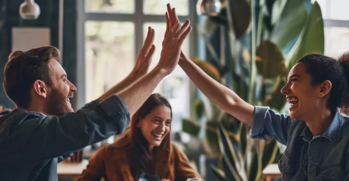 Shows two co-workers high fiving over a table