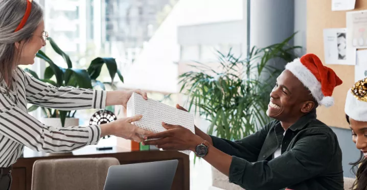 An employee giving their co-worker a holiday gift for appreciation