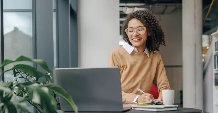 Employee smiling as they communicate at work on their laptop