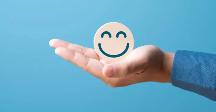 A hand holding a smiling face