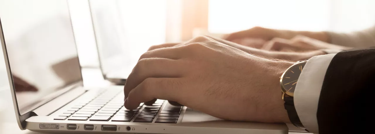 Image shows a close up of a person typing on their laptop