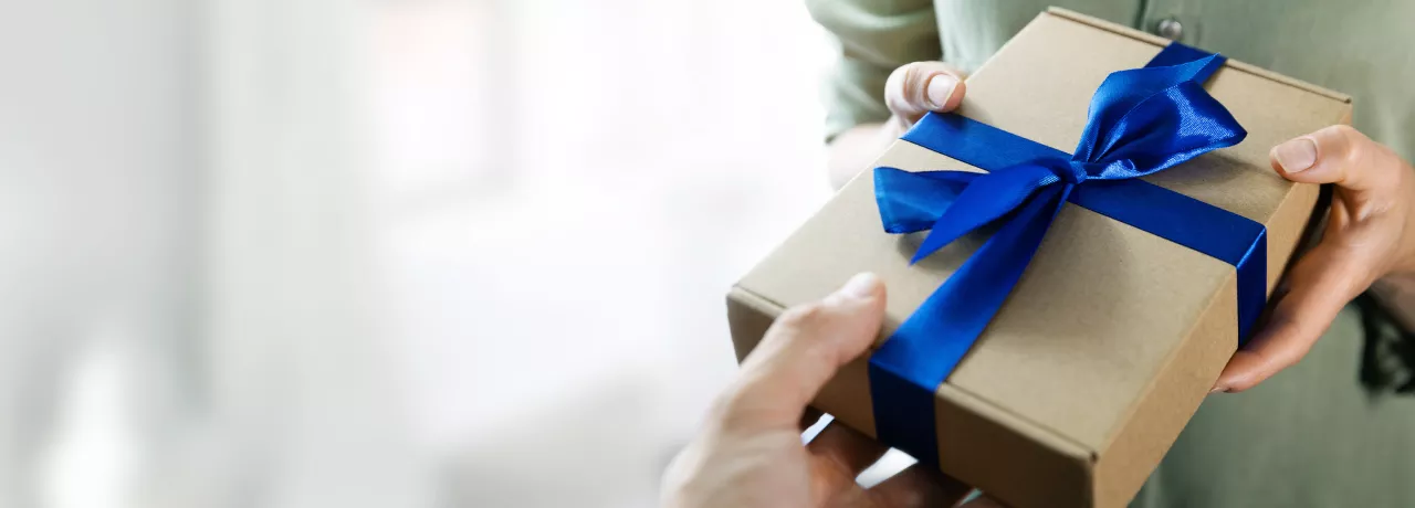 Image shows a person handing a gift to another person