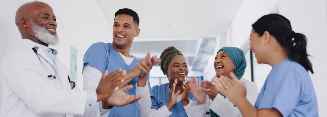 Three nurses and doctors celebrating by clapping their hands