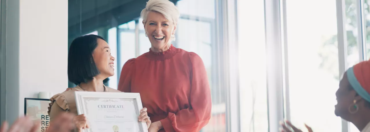 Image shows a leader presenting an employee award to a team member.