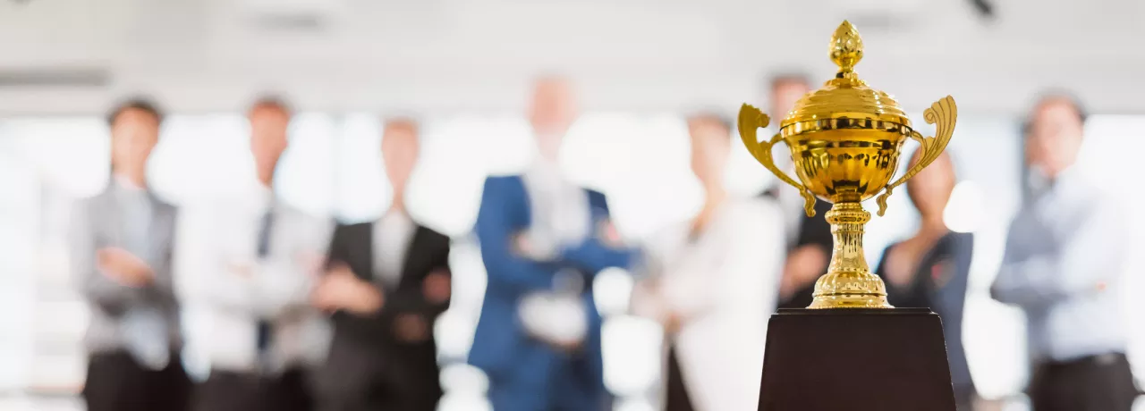 Image shows a trophy sitting in front of a group of employees