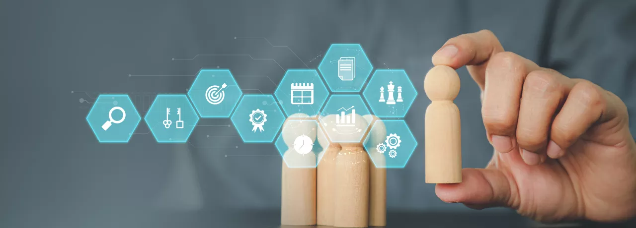 Image shows a person moving a wooden figure with various business symbols in front