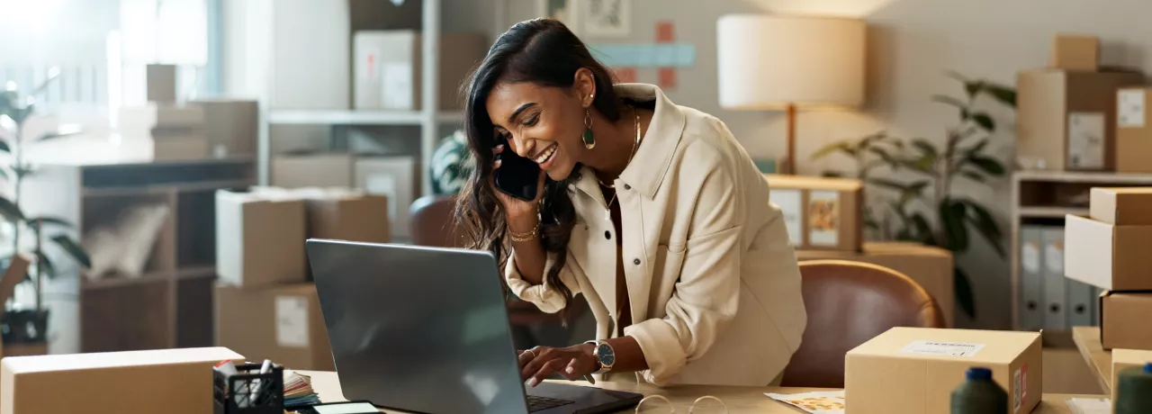 Image shows a woman looking down at her computer and smiling