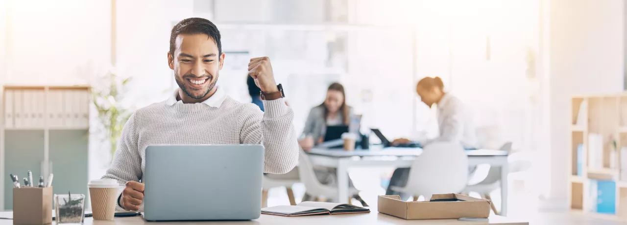 Image shows an employee celebrating by their computer.