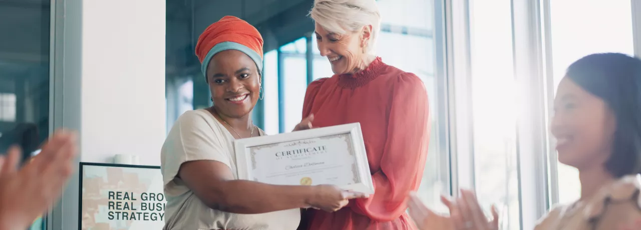 Shows a leader presenting an award to an employee