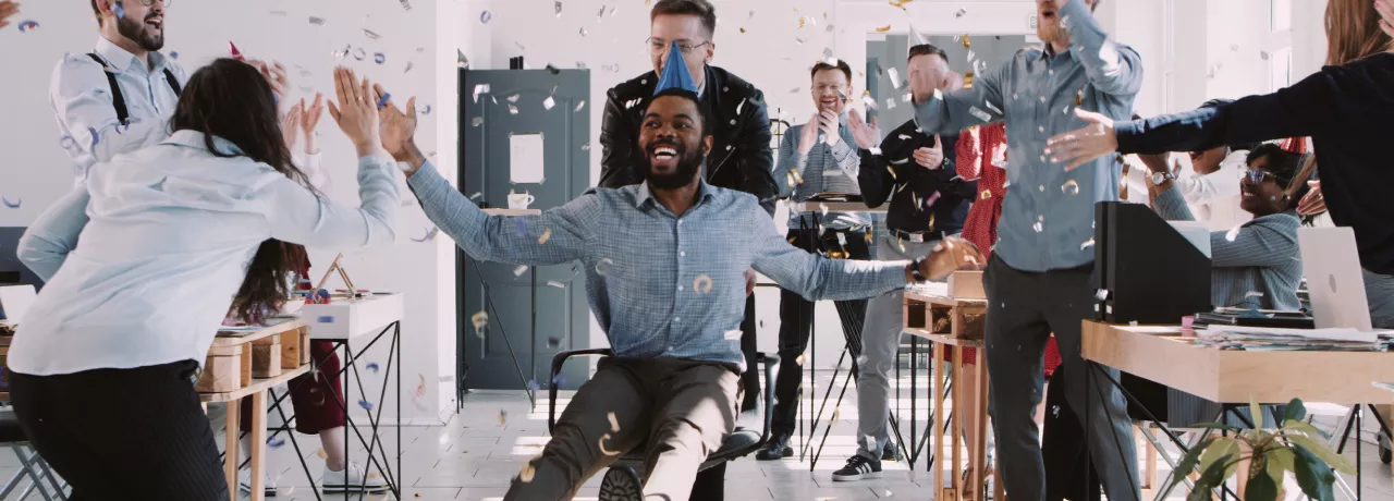 Image shows a person celebrating at an office party