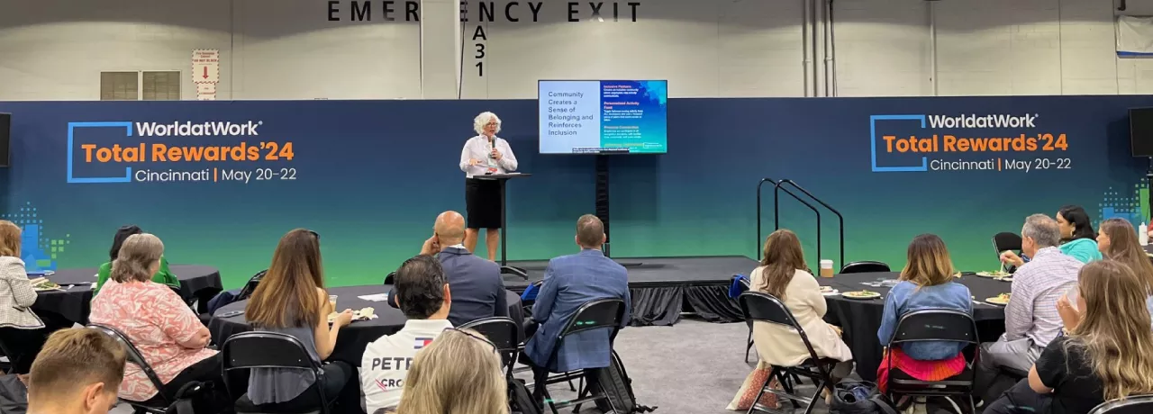 Image shows Theresa Harkins-Schulz, Inspirus SVP of Product and Customer Experience, speaking at the Total Rewards conference in front of attendees.