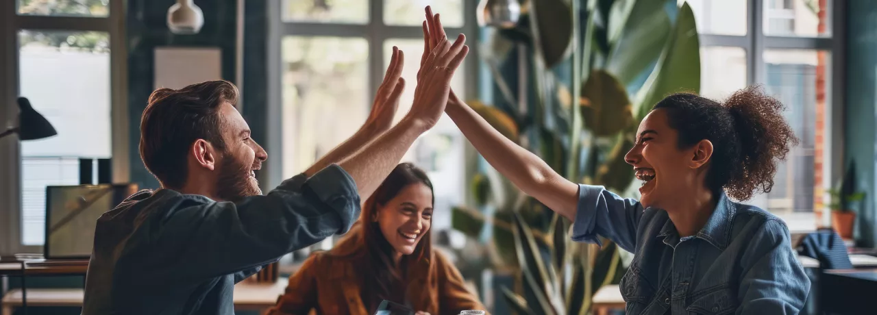 Shows two co-workers high fiving over a table
