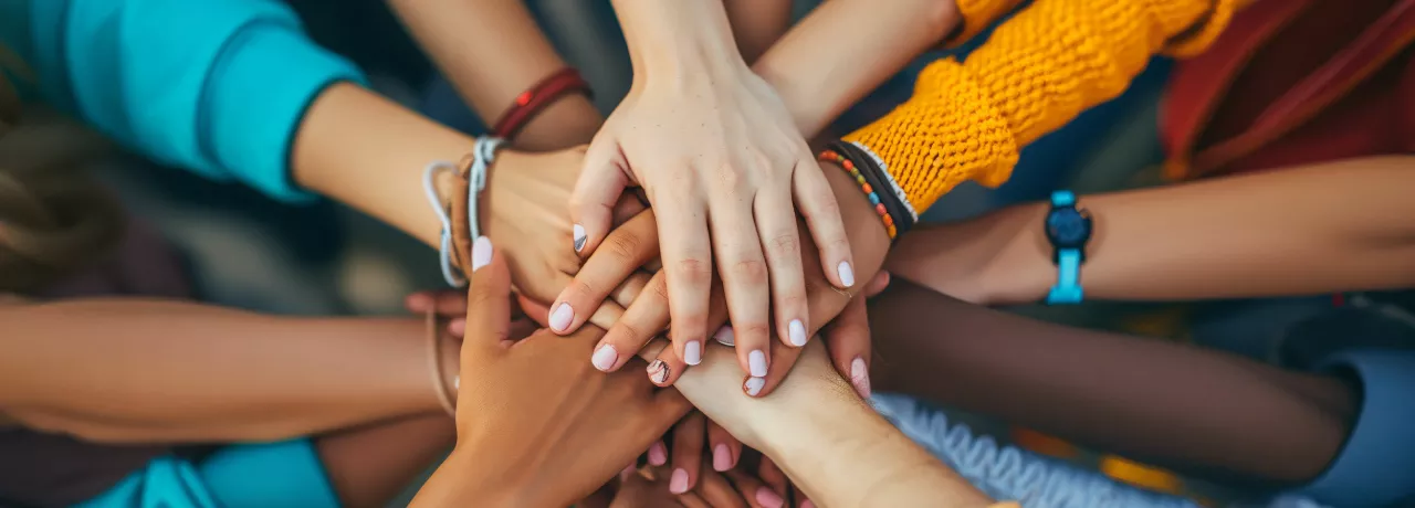 Shows a bunch of hands stacked together