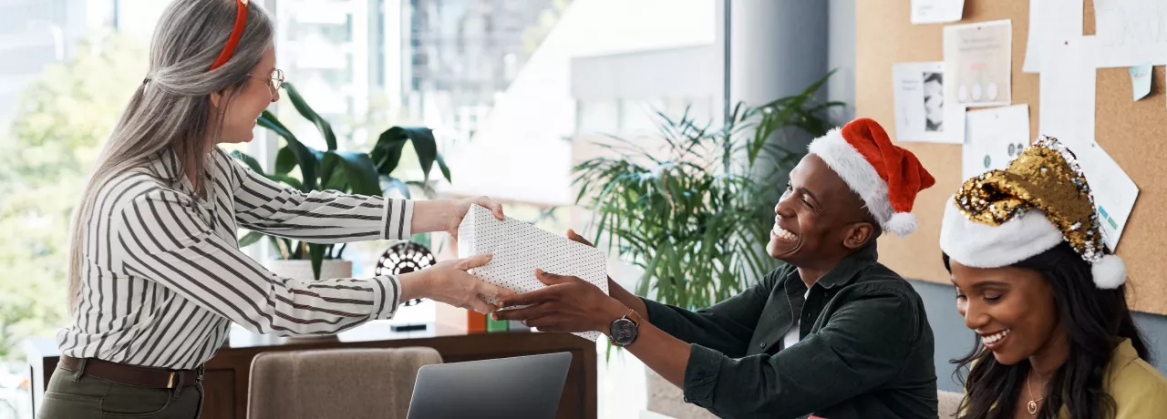 An employee giving their co-worker a holiday gift for appreciation