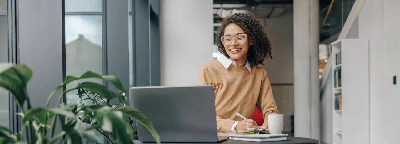 Employee smiling as they communicate at work on their laptop