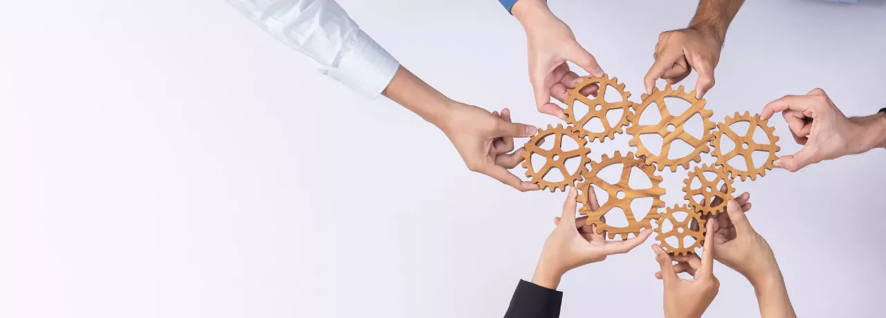 A group of employees creating a cogwheel with each holding a small cog