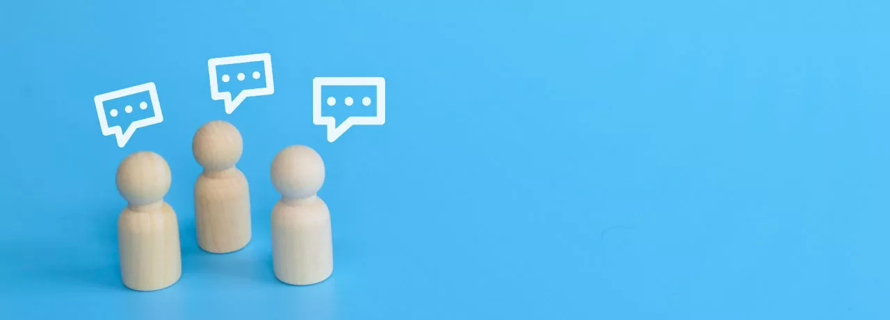 Three wood figurines giving feedback with text boxes over their head