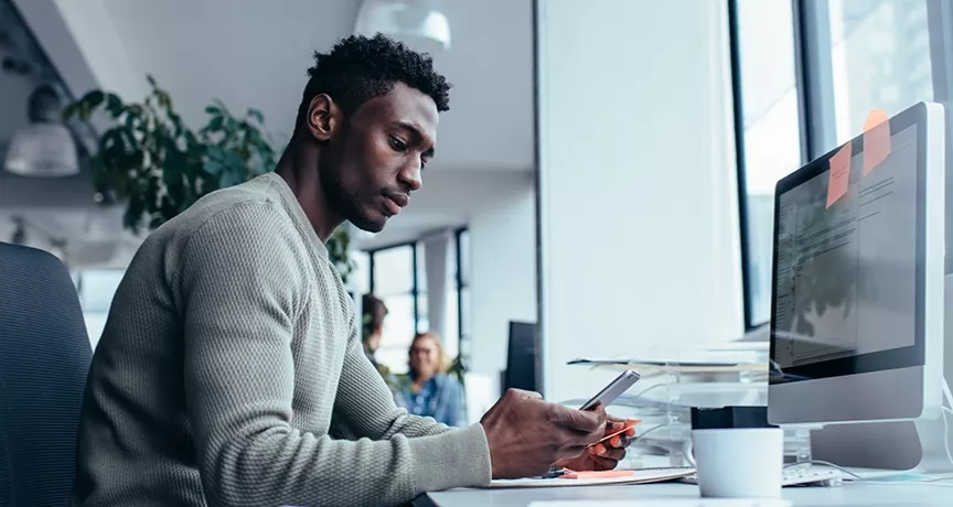 guy at desk using cell phone