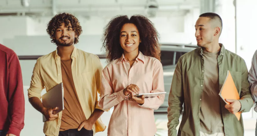 Five employees walking in an office looking happy