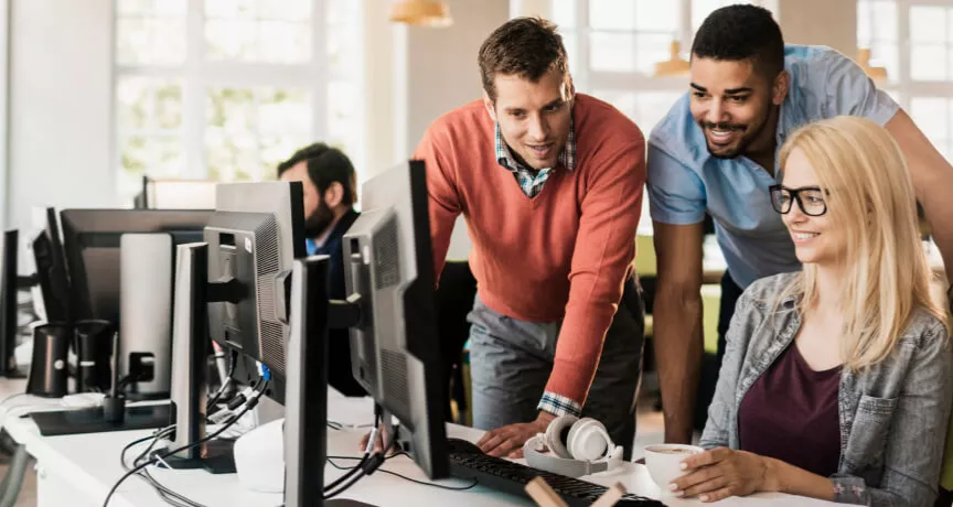 Three employees gathered around a computer